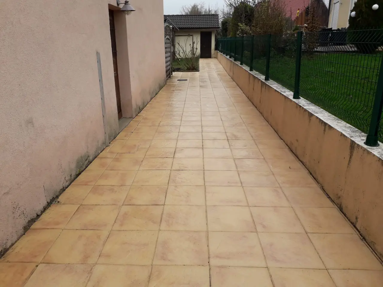 Allée carrelée nettoyée le long d’une façade.